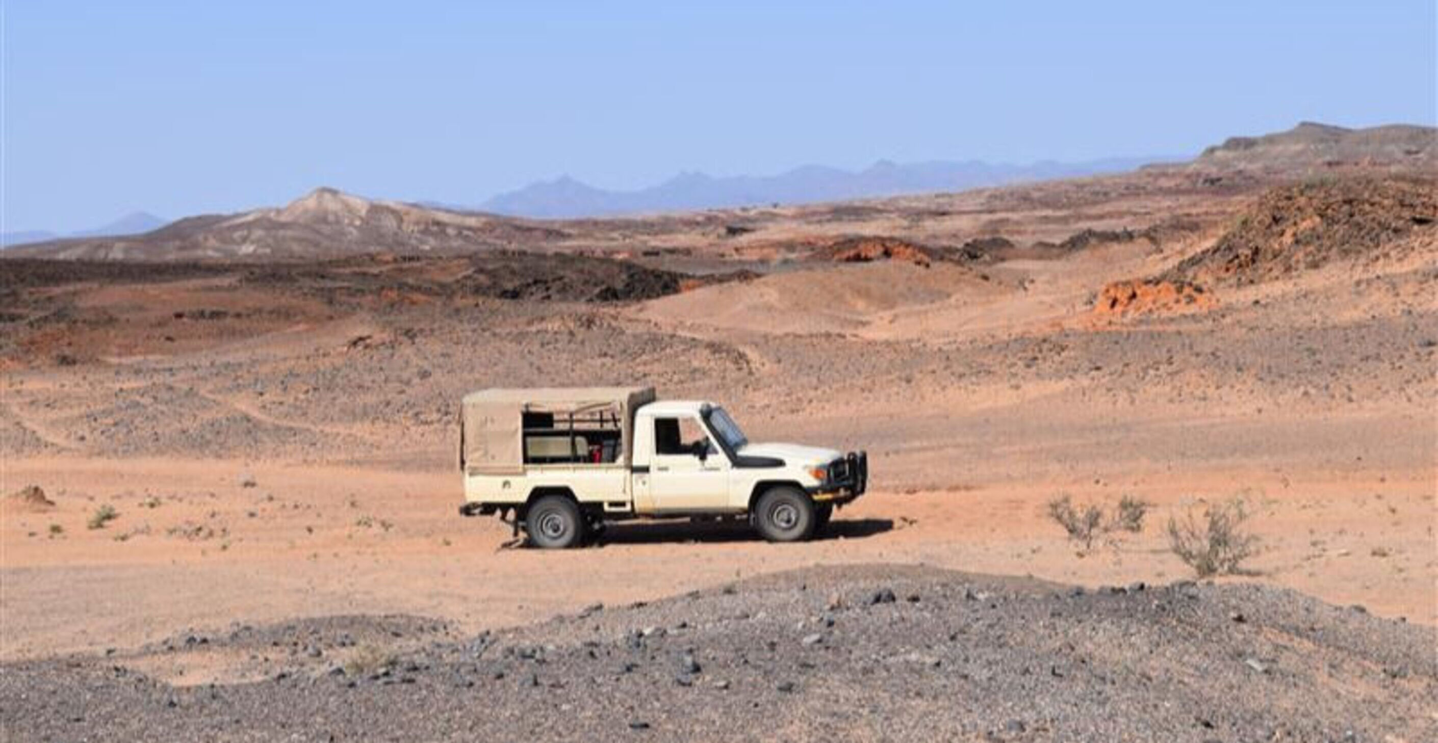 Truck in the center of Kenyan desert with hills and mountains in the background